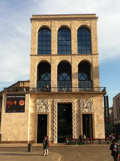 The outside of a three-storey square building with arched windowns