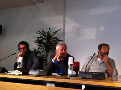 Three people sitting behind a table, each with a microphone