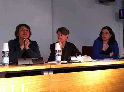 Three people sitting behind a table, each with a microphone