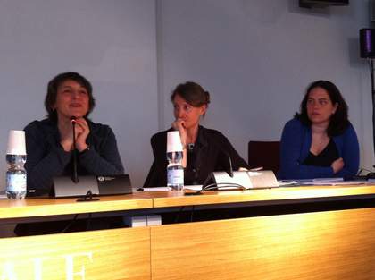 Three people sitting behind a table, each with a microphone