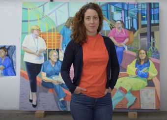 A photo of artist Aliza Nisenbaum standing in front of one of her paintings