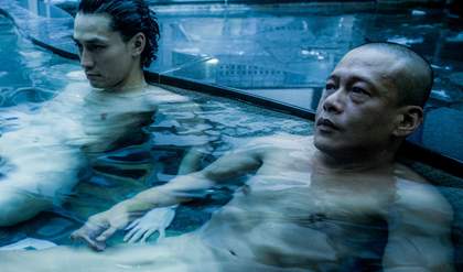 two men sit naked in a swimming pool