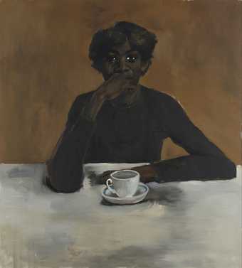 A man sits at a table with a cup of tea