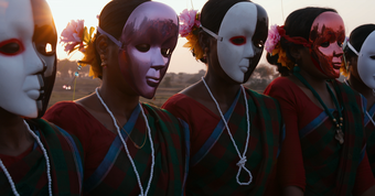 A group of figures wear colouful face masks in a still from the film O Horizon by The Otolith Group