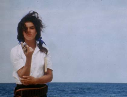 a woman in a white shirt stands in front of the sea