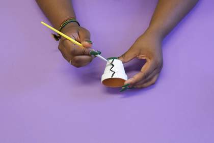 Photograph of two hands painting a plant pot