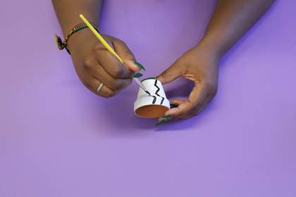 Photograph of two hands painting a plant pot