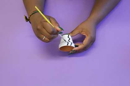 Photograph of two hands painting a plant pot