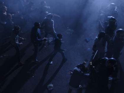 people stand and walk in the dark surrounded by police