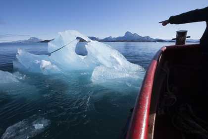 Photograph of a boat and an iceberg floating in Nuup Kangerlua, Greenland