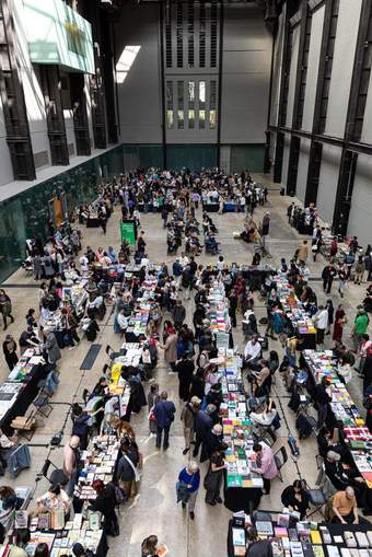 Large industrial hall with people looking at stalls of books