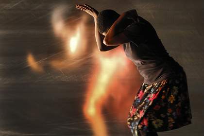 a woman crouches with a blurring image of a running person behind her