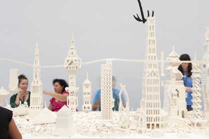 People sit and make buildings out of white lego pieces