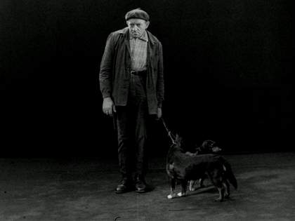 Black and white film still of "Hamburg" where two men and a woman stand next to a ladder and drop written signs.