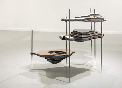 A freestanding sculpture made of layers of metal that resembles a land mass