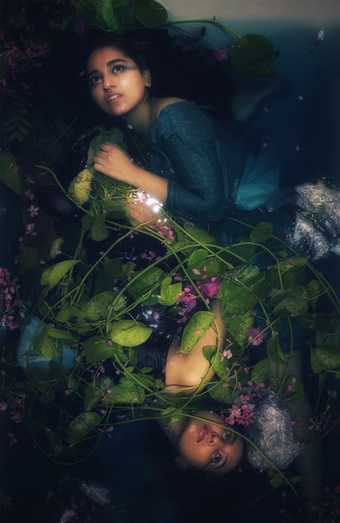 Photograph of lady underwater surrounded by flowers