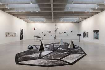 Installation view of the exhibition including large black and white patterned carpet with small sculptures on it