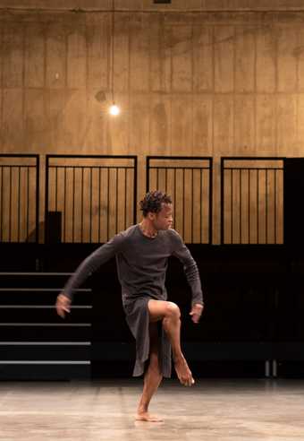 a man stands with right leg lefted in an empty auditorium