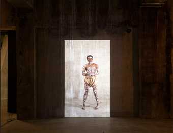 Image projection on concrete wall of a black man standing with white paint letters on his body