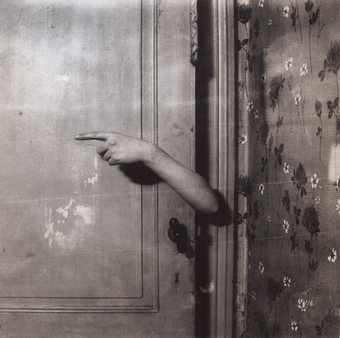 Paul Nouge Le bras revelateur from Subversion des images 1929 to 1930 Black and white photograph of an interior where an arm emerges from behind a door with a finger pointing to the left