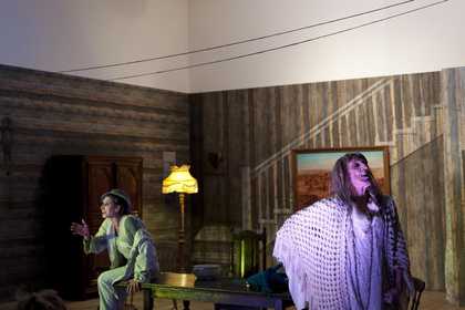 Close up of characters performing a dialogue in a theatre set of a living room
