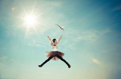 A girl dressed in fairy wings jumps in the sky