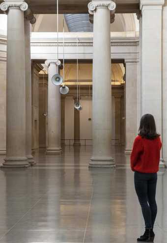 A woman stands and looks at the Susan Philipsz installation