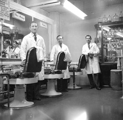 black and white photograph of three men inside a barber shop circa 1949 - 1956