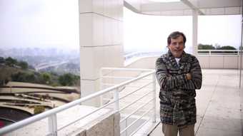 Photograph of Richard Tuttle on a white balcony with arms folded across his chest