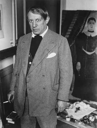 Brassaï, photo of Picasso in his studio at 23 rue La Boétie, standing in front of Rousseau’s Portrait of a Woman 1932