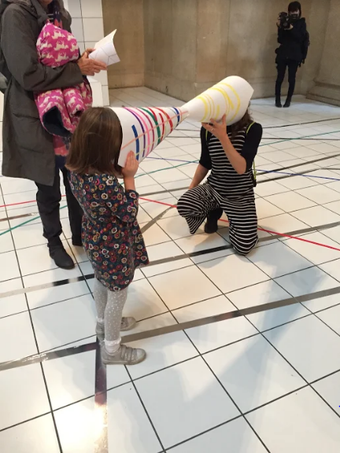 A child and adult look at each other through paper cones