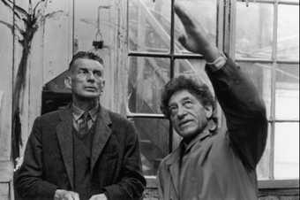 A black and white photograph of Samuel Beckett and Alberto Giacometti in Giacometti's studio