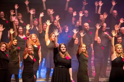 LGBTQ Choir standing with arms in air