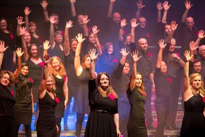 LGBTQ Choir standing with arms in air