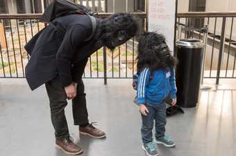 an adult and a child wearing guerrilla masks 