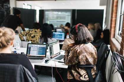 A group of girls at a table producing beats on laptops