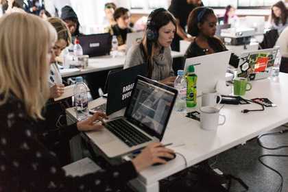 A group of people sitting at a table producing music on laptops