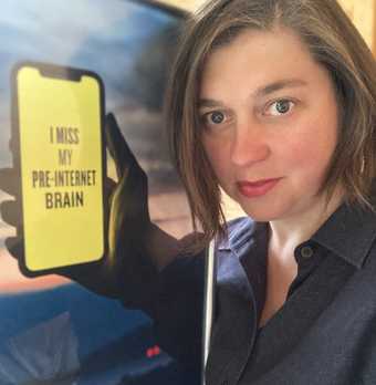 Head and shoulders of a person next to a poster showing a hand holding a phone on which is written 'I miss my pre-internet brain'. The poster is positioned so the hand appears to belong to the person.