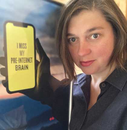 Head and shoulders of a person next to a poster showing a hand holding a phone on which is written 'I miss my pre-internet brain'. The poster is positioned so the hand appears to belong to the person.