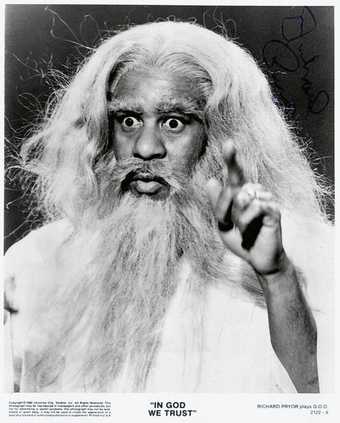 Promotional photo of Richard Pryor in the film In God We Trust 1980 image of a man with a long white beard and hair his finger is pointing upwards
