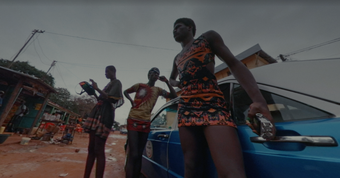 Three figures standing in front of a car shot from a low angle