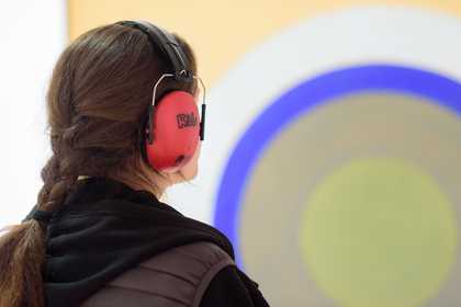 Visitor, wearing ear defenders, looking at an artwork