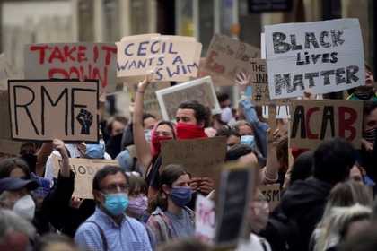 Crowd of protesters, some wearing virus protection face coverings, some holding up placards reading Black Lives Matter, RMF with the BLM fist logo, Take It Down, Cecil Wants a Swim, ACAB
