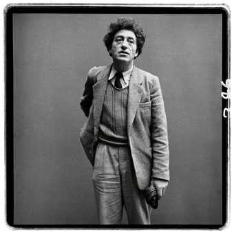 A black and white photograph of Alberto Giacometti wearing at suit, taken by Richard Avedon