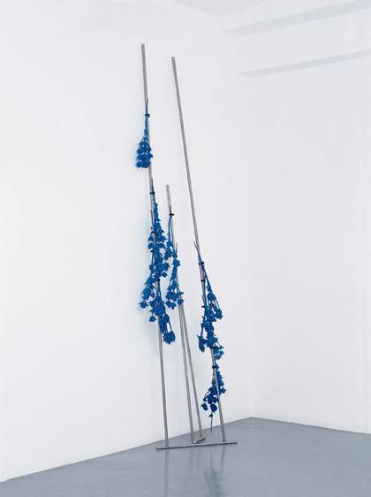 Roger Hiorns Discipline 2002 metal rods leaning against the gallery walls with blue flowers attached  