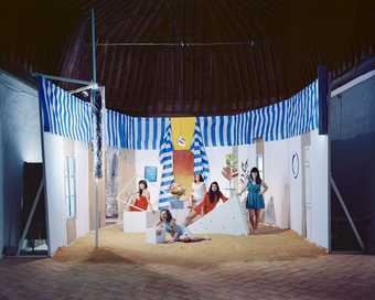 Three women sit in a pop up beach