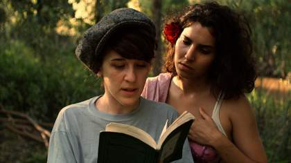 image of two woman one reading a book in the foreground and one looking over the other's shoulder