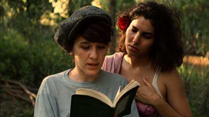 image of two woman one reading a book in the foreground and one looking over the other's shoulder