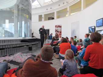 Tate St Ives story telling event for  families; photograph of audience and reader in Tate St Ives loggia