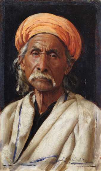 Front on portrait of Indian man staring straight ahead wearing an orange turban